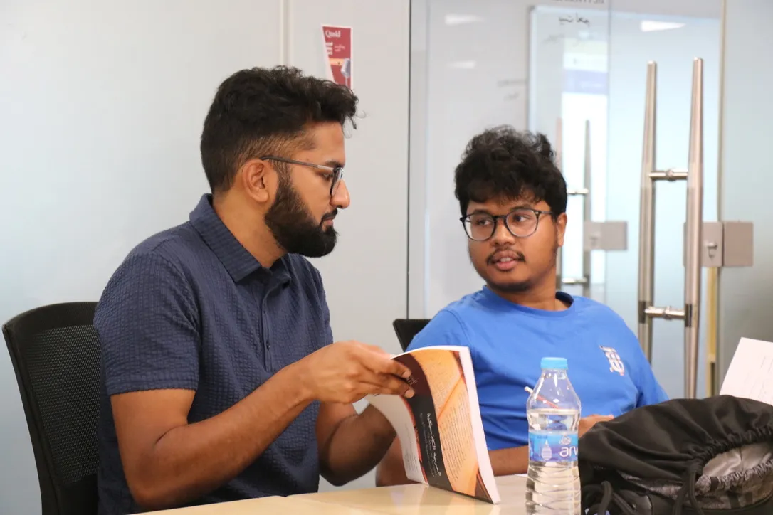 Two students working through an Arabic textbook together in class